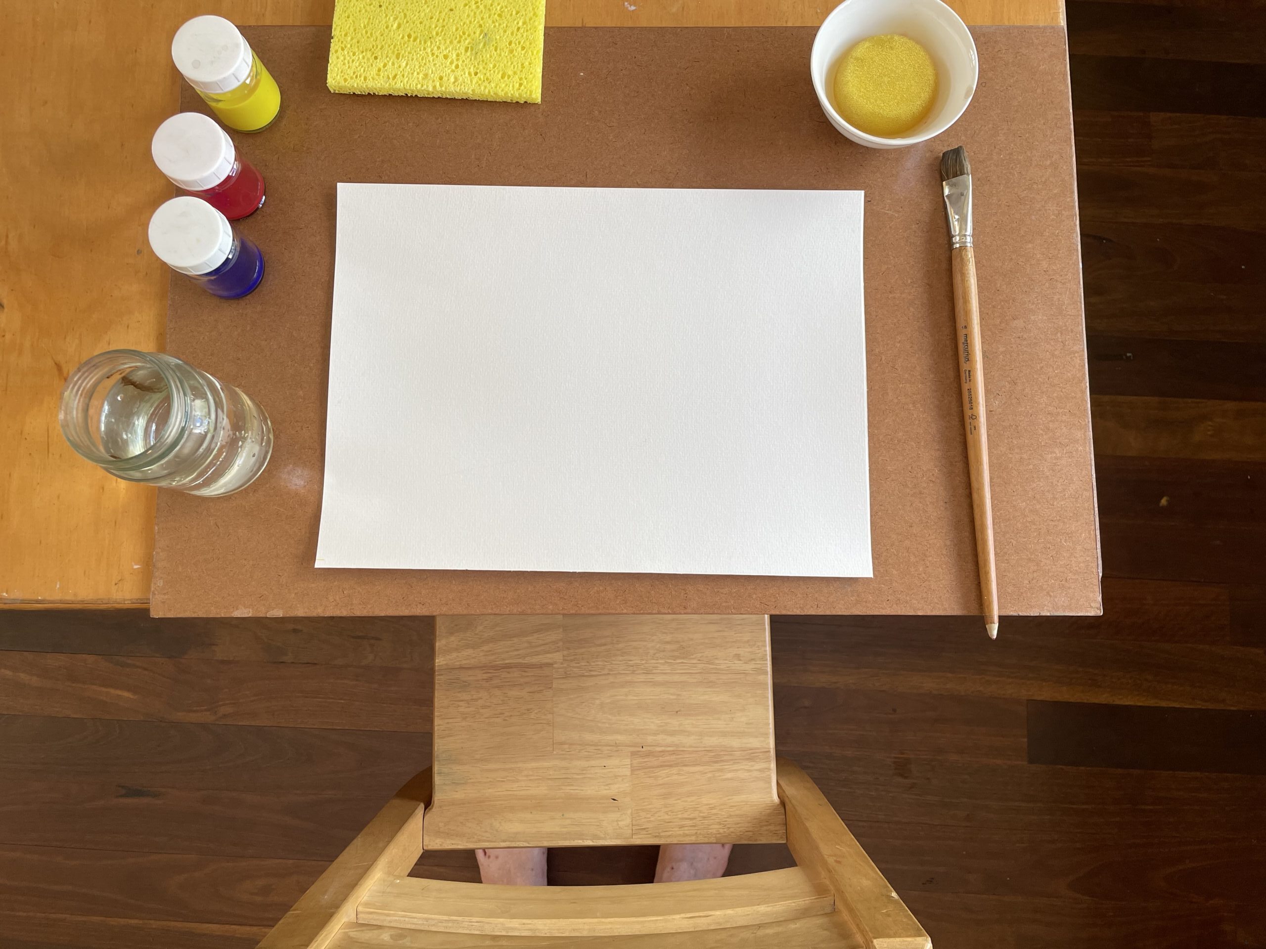 Desk with watercolour paper, paint, brush, sponge, water